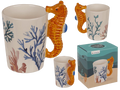 Taza original blanca con corales dibujados y asa en forma de caballito de mar naranja, vista con caja de regalo