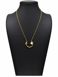 Collar dorado de mujer con colgante curvo abierto, nudo decorativo y perla blanca, sobre expositor negro y fondo blanco