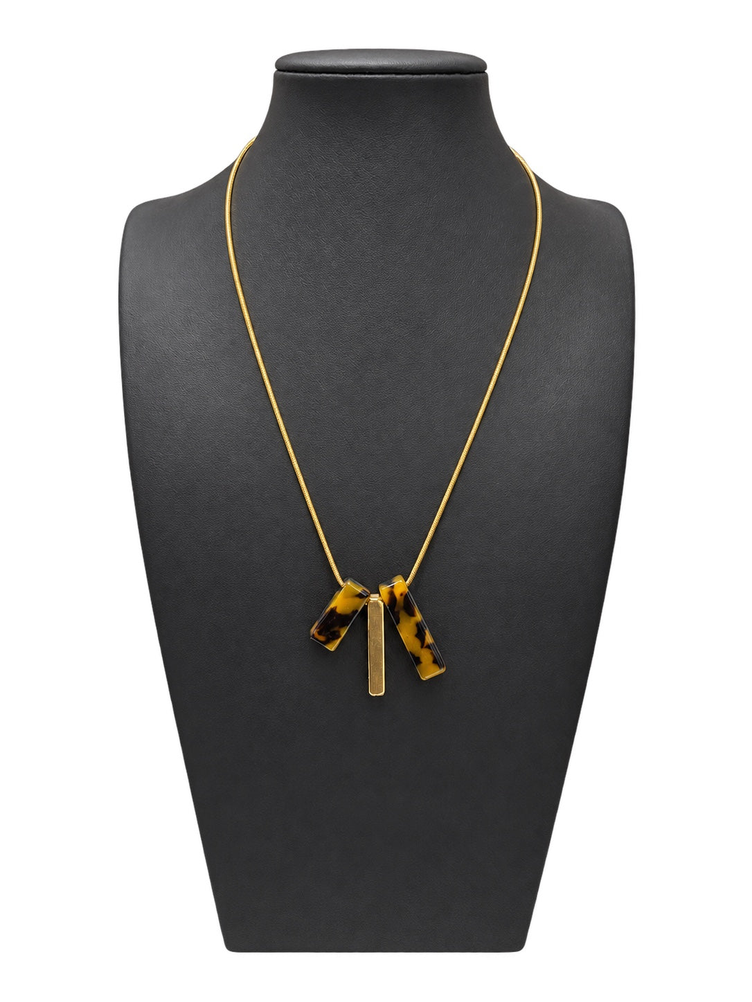 Collar de mujer de cadena dorada fina con tres piezas colgantes, dos de efecto carey y una barra dorada, sobre busto negro y fondo blanco