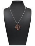 Collar Eclipse con cadena plateada y colgante de luna y sol en tono cobrizo sobre busto negro y fondo blanco
