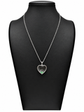 Collar Iris plateado con corazón transparente, flor y detalles verdes sobre expositor negro